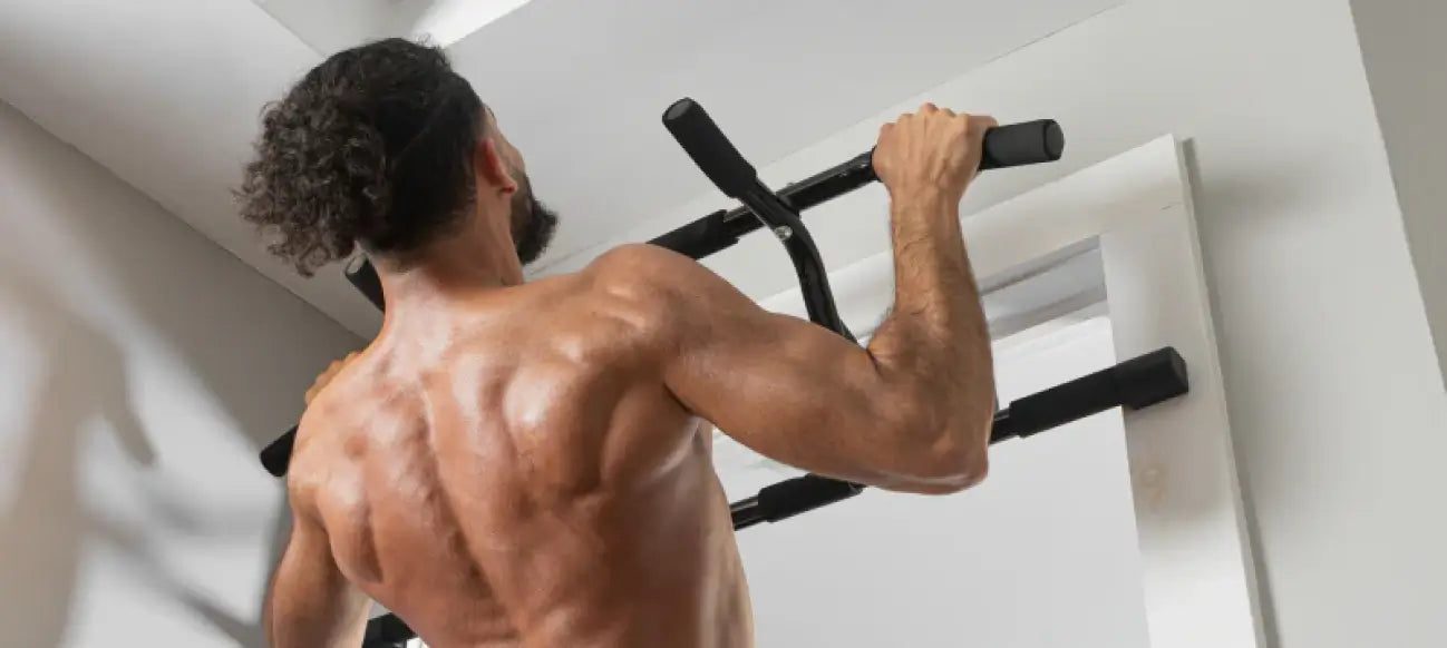 Man pulling himself up on the DMoose doorway pull-up bar, seen from behind with his back and shoulder muscles engaged