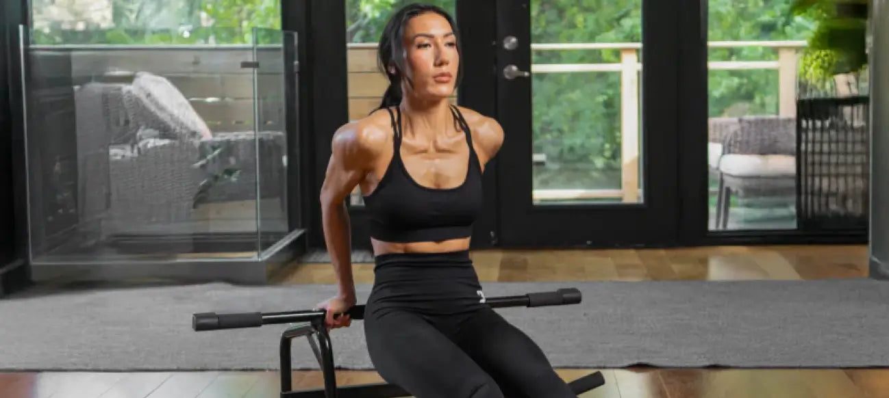 Woman training on her living-room floor with the DMoose pull-up bar set down as a dip and push-up station